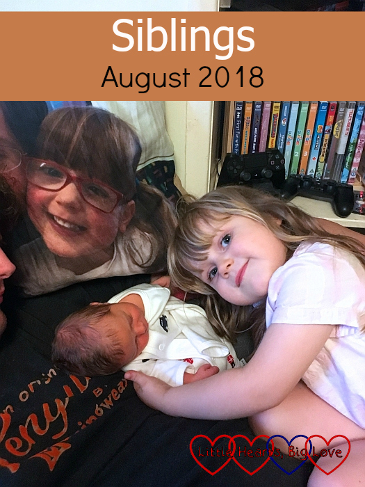Sophie cuddling Thomas with the cushion showing Jessica looking on - "Siblings - August 2018"