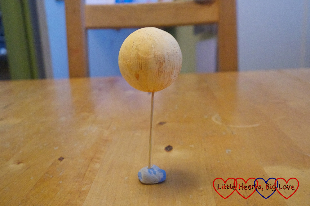 A painted polysyrene ball on top of a cocktail stick stuck in blu tack