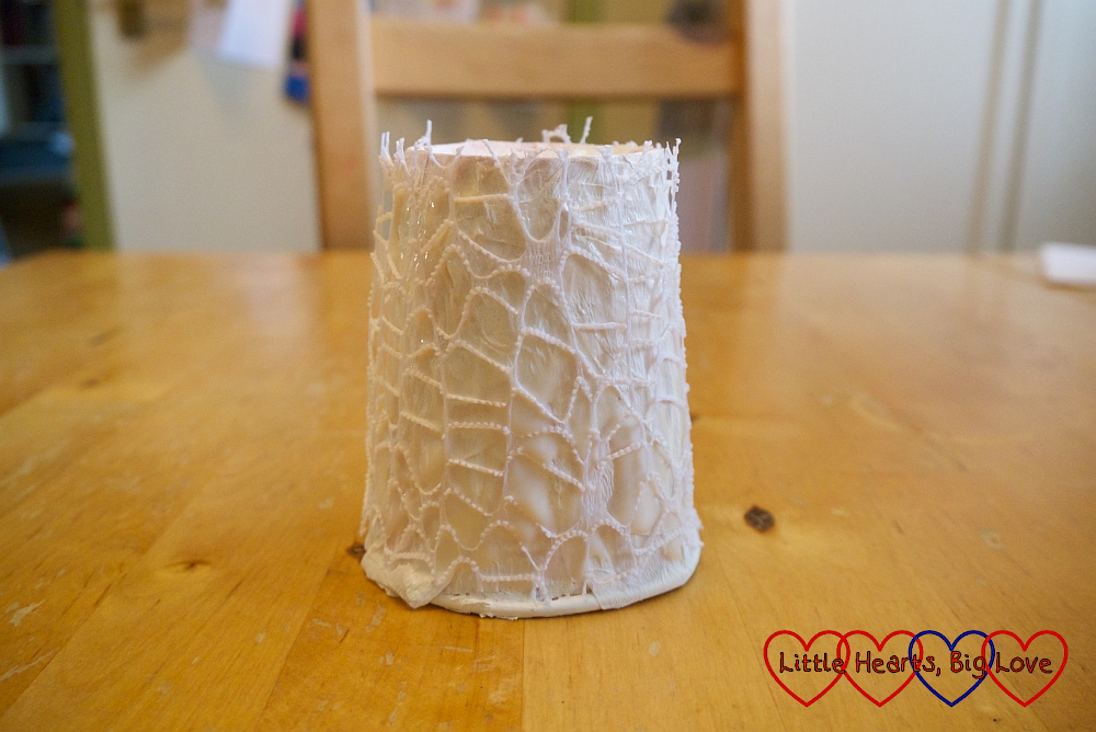 An upturned paper cup wrapped in white crepe paper and lacy fabric