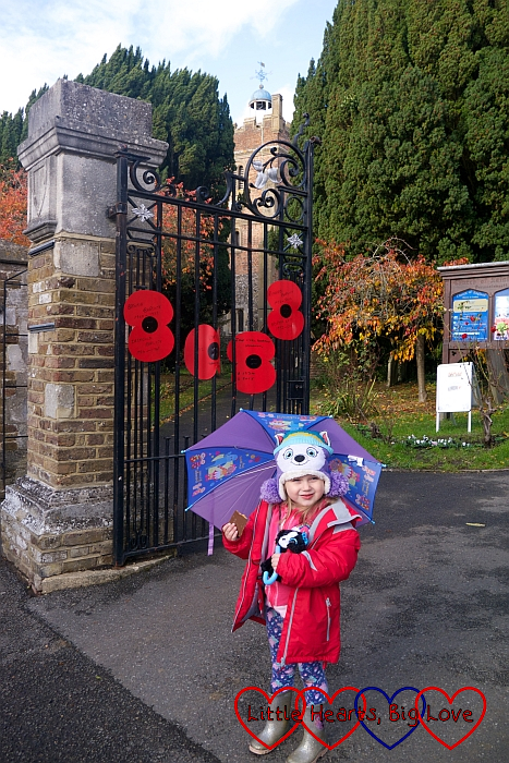 Sophie outside St Mary's church with the gates decorated with red poppies