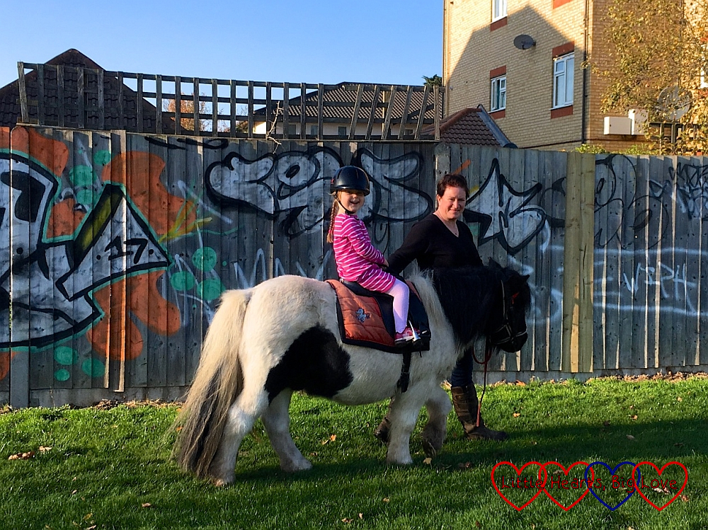 A very smiley Sophie riding a white and brown Shetland pony