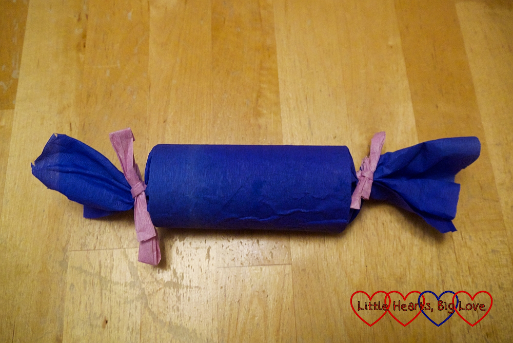 The crepe-paper wrapped toilet roll tube with the ends tied with raffia