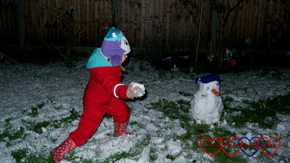 Sophie throwing snowballs at her snowman