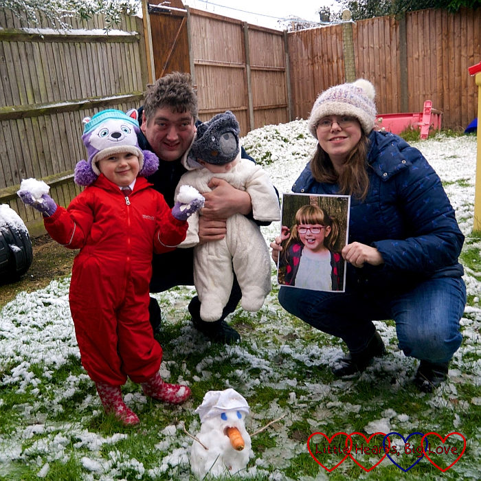 Sophie, hubby, Thomas and me holding a picture of Jessica next to the snowman Sophie built