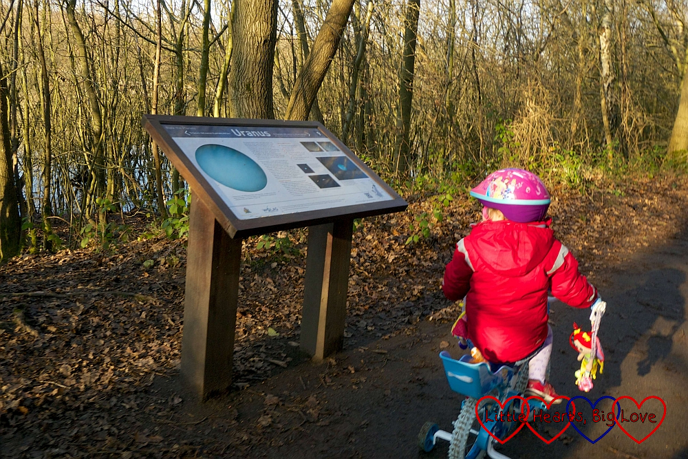 Sophie passing the Uranus information board on her bike