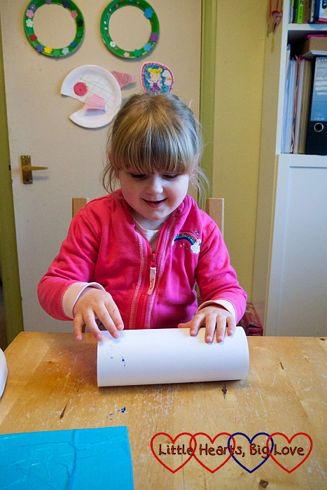 Sophie wrapping white paper around the cardboard tube