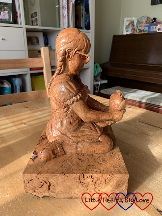 The wooden sculpture of Jessica kneeling holding her Kerry doll