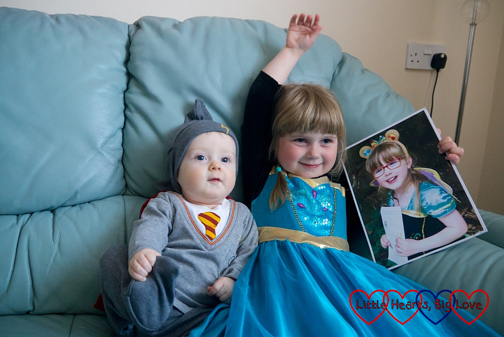 Thomas in a Harry Potter sleepsuit and Sophie in a princess dress holding a picture of Jessica in a princess dress