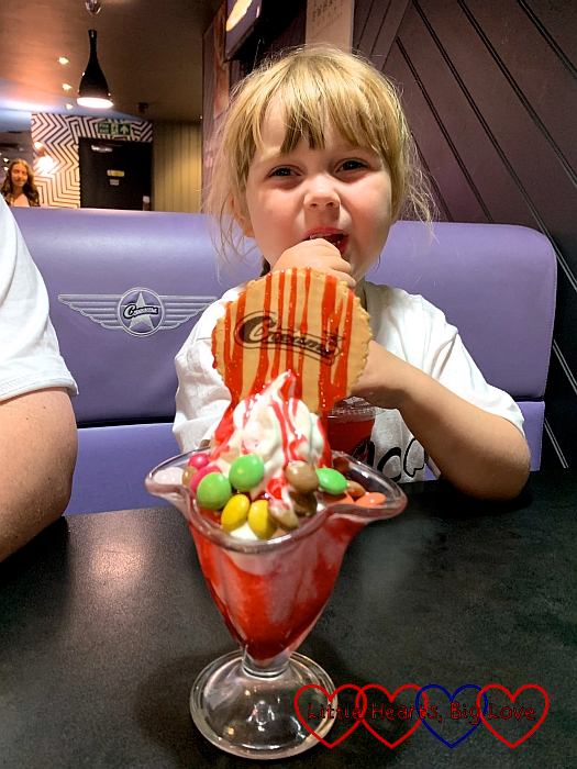 Sophie with an ice-cream sundae with Smarties on top, a wafer and strawberry sauce