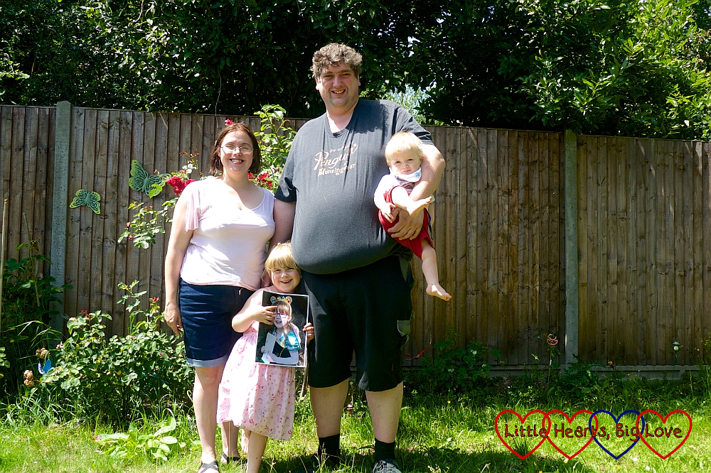 Me, hubby holding Thomas, and Sophie holding a photo of Jessica in the garden in the sunshine