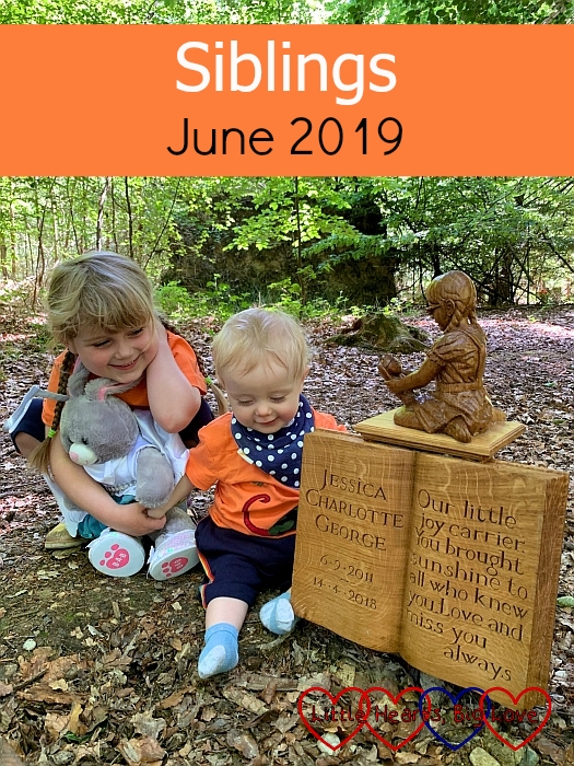Sophie (holding her Jessica bunny) and Thomas in matching shorts and T-shirts sitting next to the sculpture of Jessica at her forever bed - "Siblings - June 2019"
