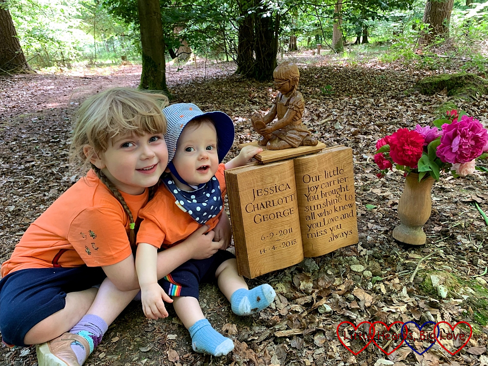 Sophie and Thomas in matching shorts and T-shirts sitting next to the sculpture of Jessica at her forever bed