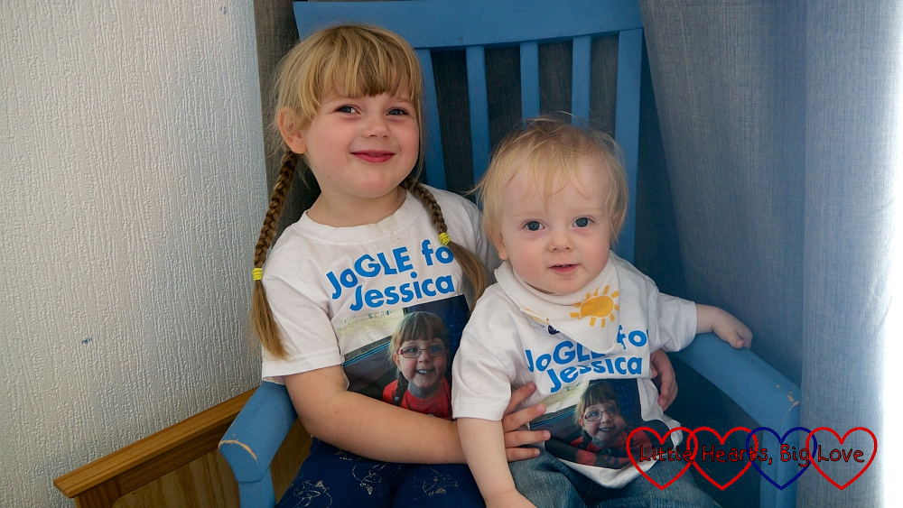 Sophie and Thomas sitting in a blue chair wearing their "JoGLE for Jessica" T-shirts