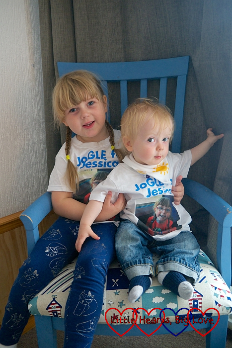 Sophie and Thomas sitting in a blue chair wearing their "JoGLE for Jessica" T-shirts