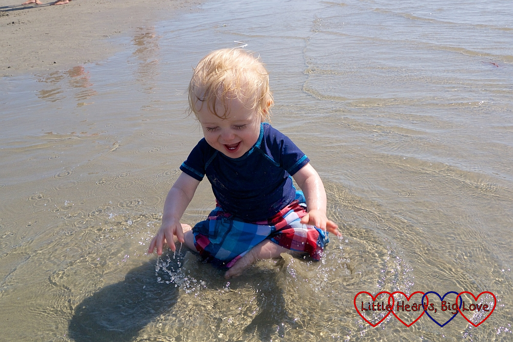 A very happy Thomas splashing in a shallow pool on the beach
