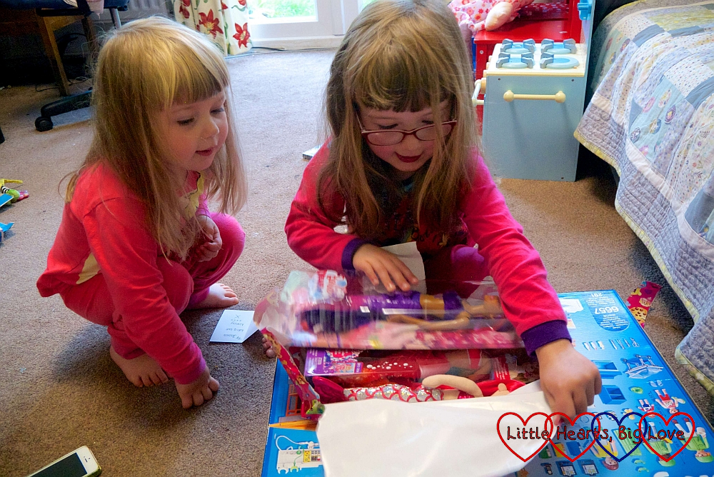 Jessica unwrapping birthday presents on her sixth birthday while Sophie looks on