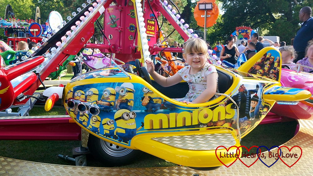 Sophie riding on a yellow Minions aeroplane at the funfair