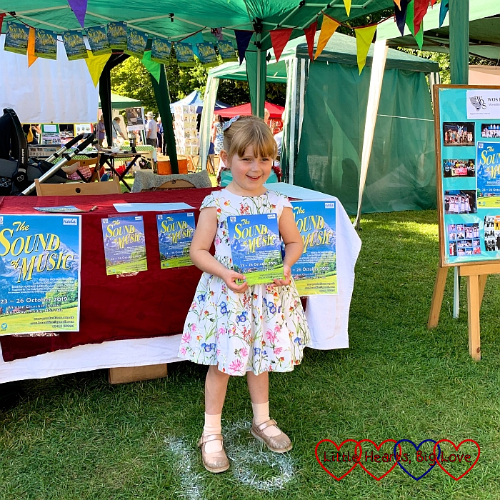 Sophie standing in front of the WOS Productions stand holding a Sound of Music flyer