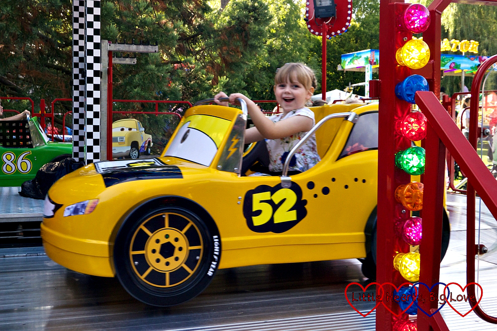 Sophie driving a yellow car at the funfair