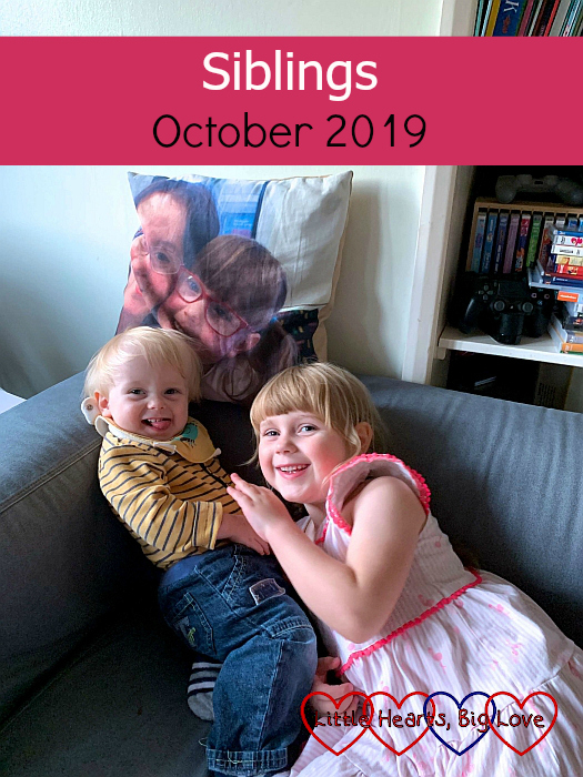 Thomas and Sophie cuddling on the sofa in front of Jessica's photo cushion - "Siblings - October 2019"