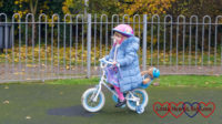 Sophie riding her bike around the park with Walter strapped into the seat behind her