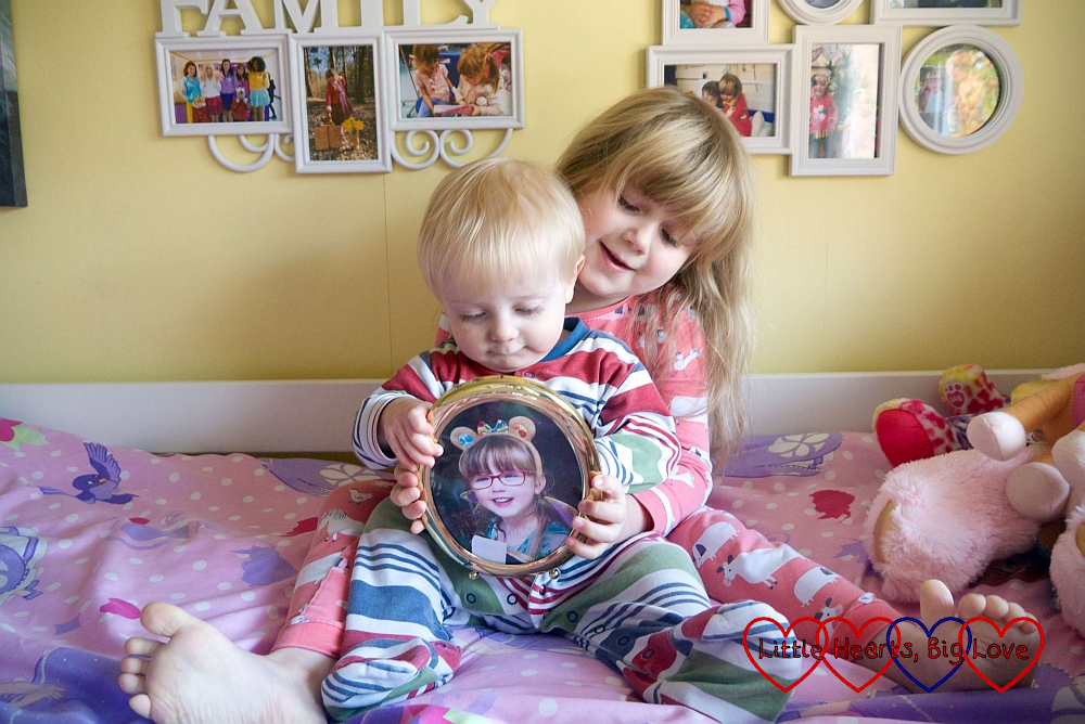 Sophie sitting on her bed with Thomas on her lap, holding a photo of Jessica