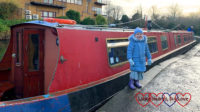 Sophie standing in front of a red narrowboat
