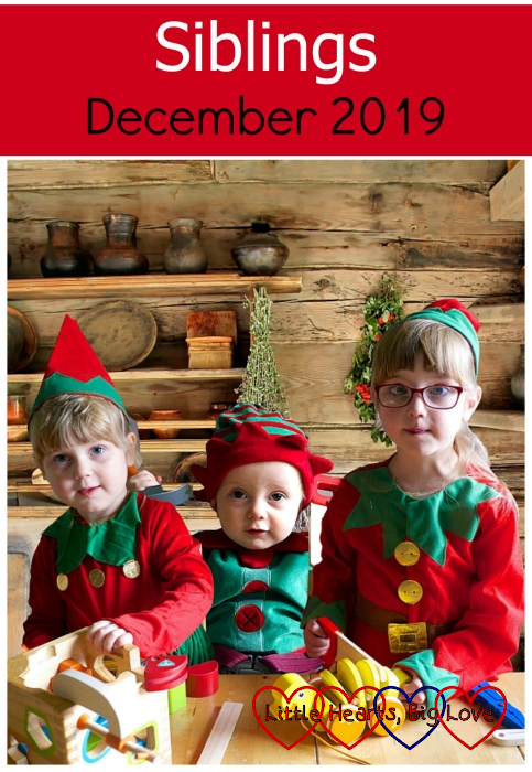 Sophie, Thomas and Jessica dressed as Christmas elves at the table together with a log cabin background - "Siblings - December 2019"