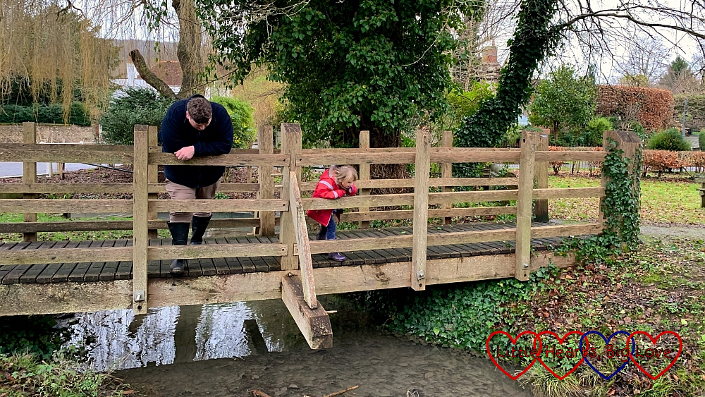 Daddy and Sophie playing Poohsticks on a wooden bridge over a stream