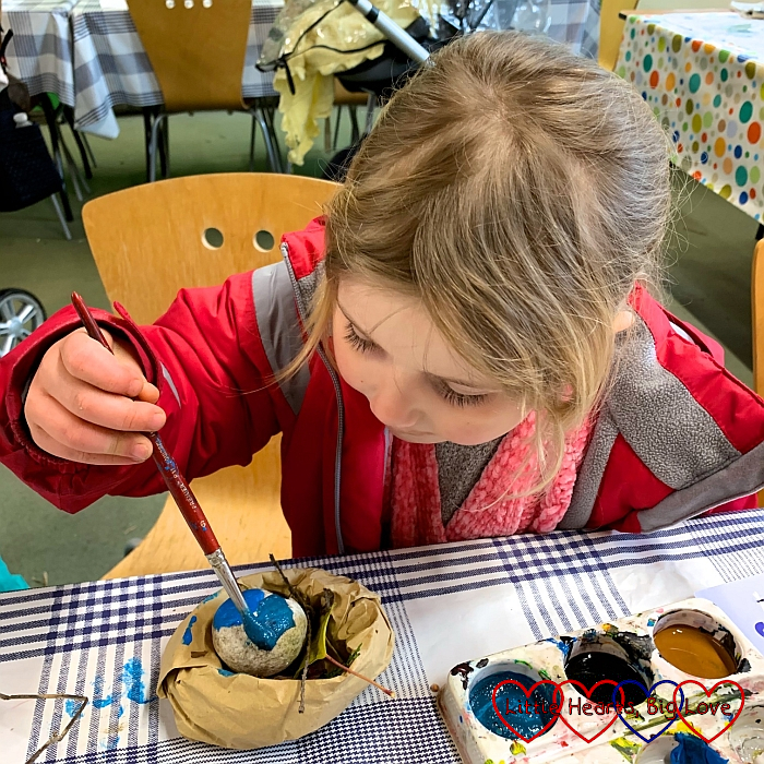 Sophie painting her rock egg with blue paint