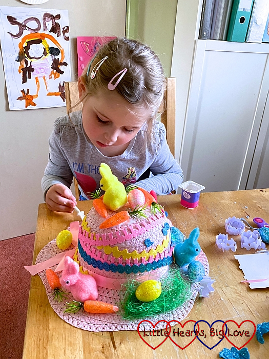 Sophie decorating a pink Easter bonnet with colourful bunnies and eggs