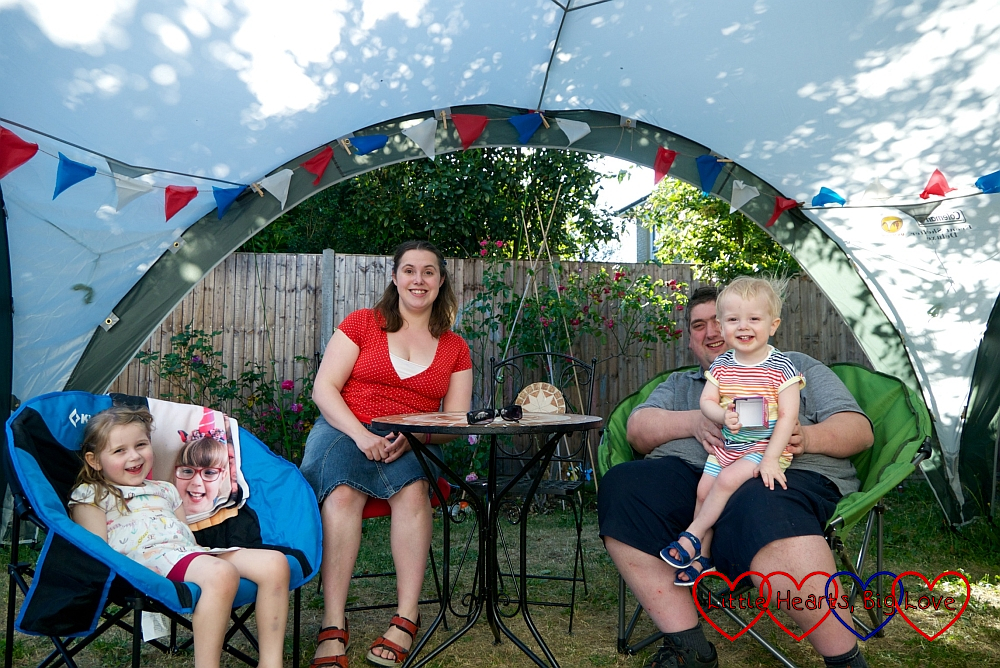 Sophie, me and hubby (holding Thomas) sitting on garden chairs in the "party tent" with Jessica's photo draped over Sophie's chair