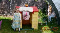 Sophie and Thomas standing by their playhouse, with Jessica's photo blanket hanging down from the roof and bubbles coming from the bubble machine on top of it