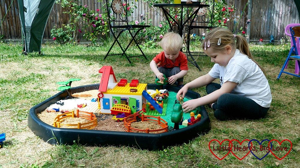Sophie and Thomas playing together with a farm scene set up in the tuff tray