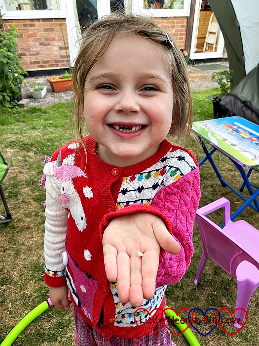 Sophie holding her tooth out in the hand and showing a very gappy smile