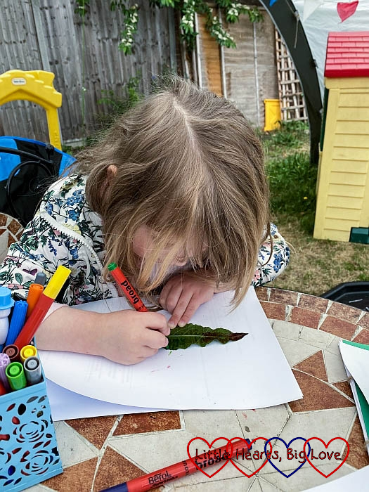 Sophie colouring in the back of a leaf with a green marker pen