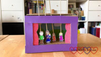 Sophie's shoebox theatre with cartoon figures of me holding Thomas, hubby, Jessica and Sophie stuck to wooden skewers