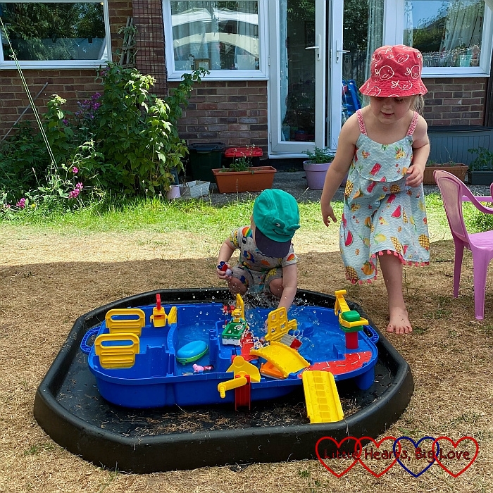 Thomas playng with his AquaPlay lock box in the garden with Sophie next to him