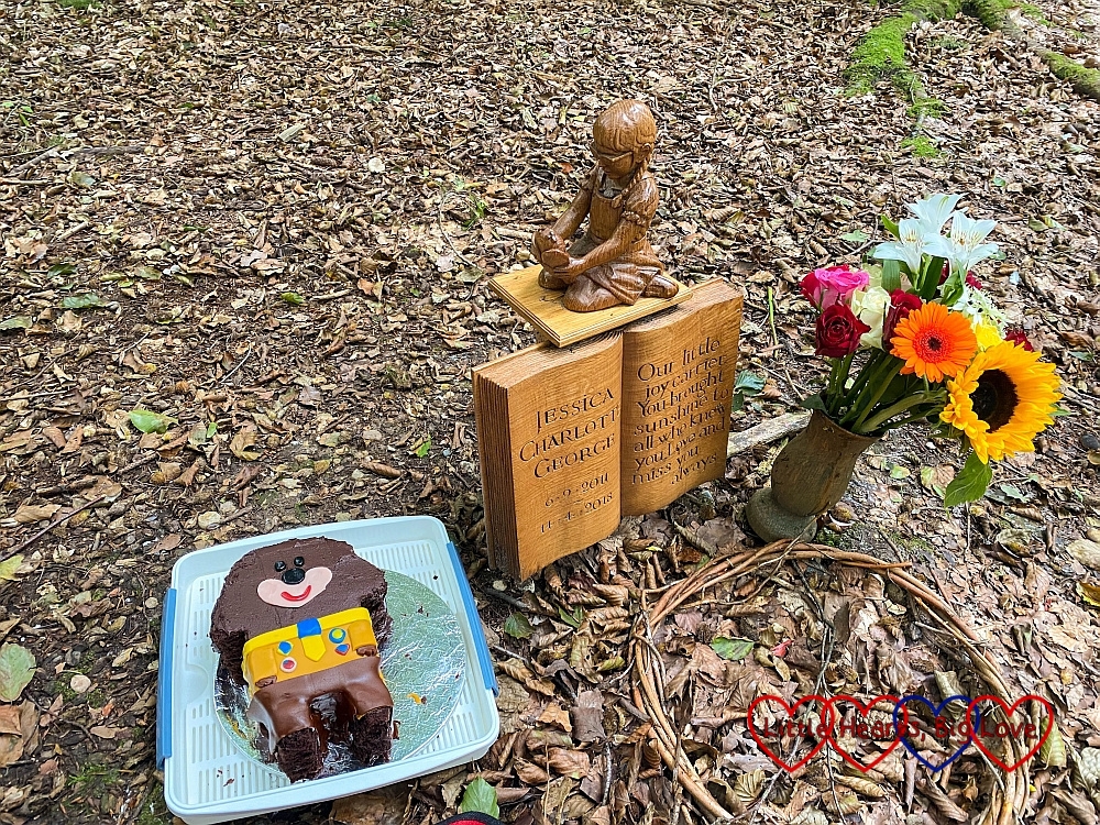 A Hey Duggee cake and a vase of flowers either side of Jessica's memorial at her forever bed