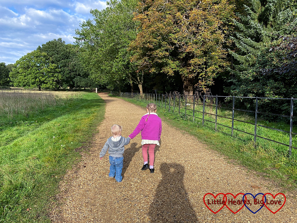 Sophie and Thomas walking hand-in-hand along a gravel path at Langley Park