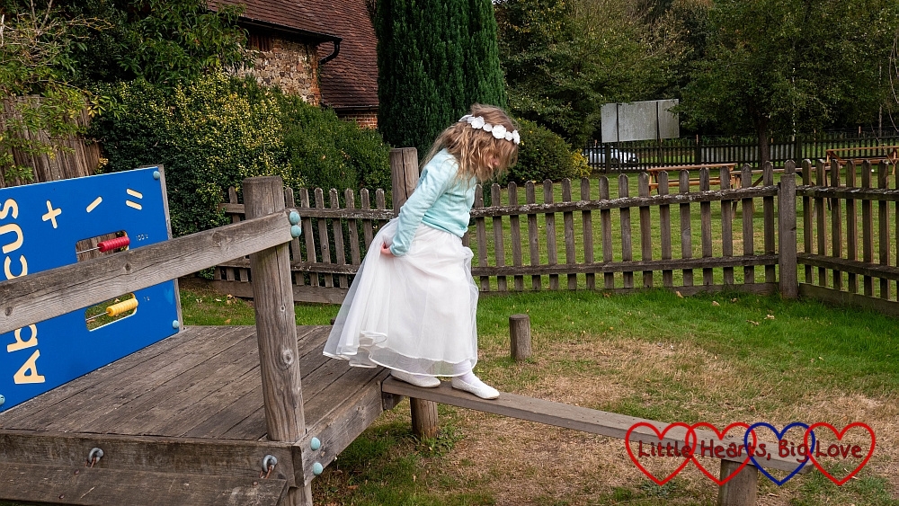 Sophie in her bridesmaid dress walking along a wooden plank