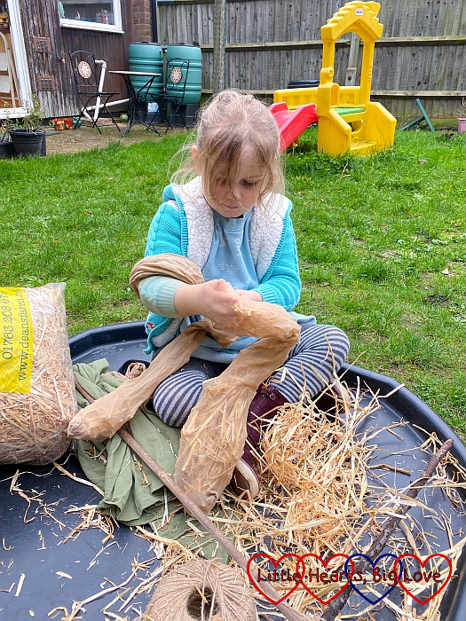 Sophie stuffing straw into tights to make scarecrow arms