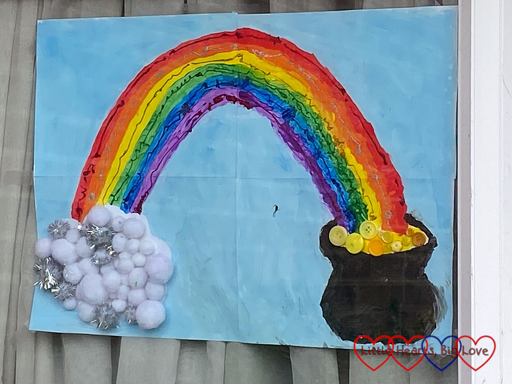 A painting of a rainbow with a pot of gold with yellow buttons for gold and white pom-poms making a fluffy cloud at the other end