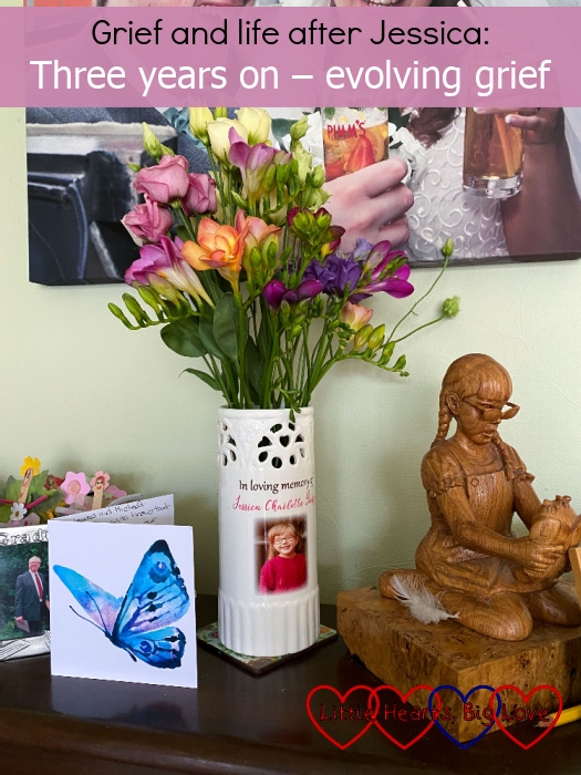 A card with a blue butterfly; a vase with Jessica's photo on full of pink and purple flowers, a wooden carving of Jessica and a photo of her on my piano - "Grief and life without Jessica: Three years on - evolving grief"