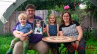 Hubby (holding a photo of Jessica) with Thomas sitting on his lap, Sophie and me out in the garden
