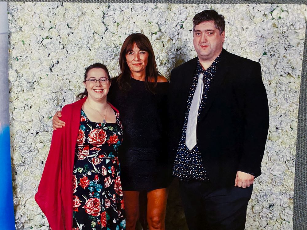 Me and my husband standing in front of a flowery wall with Davina McCall