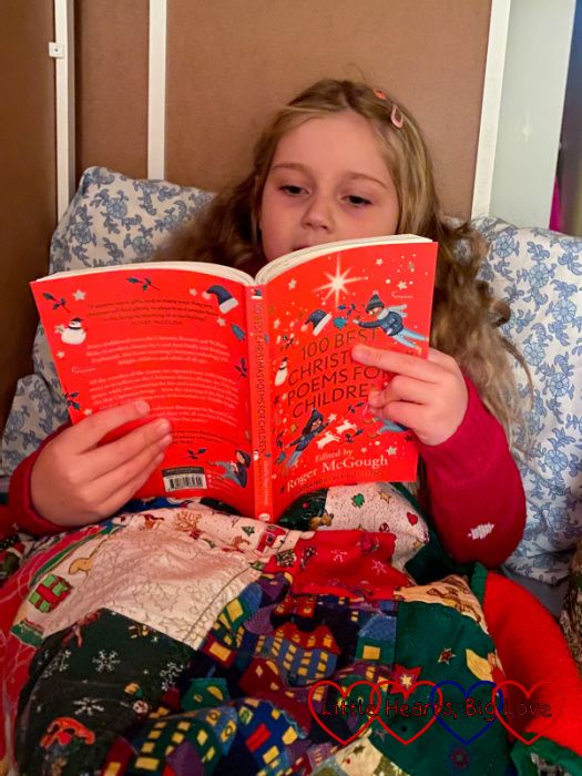 Sophie in her reading den reading a copy of '100 Best Christmas Poems for Children'