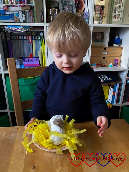 Thomas with his cardboard tube Jesus in a paper bowl manger filled with shredded yellow tissue paper
