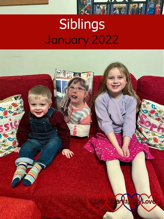 Thomas and Sophie sitting on a red sofa with a 'Jessica' cushion one side and a 'Sophie' cushion the other, and Jessica's picture on her photo blanket in between them - "Siblings - January 2022"