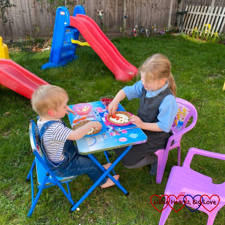Thomas and Sophie sitting at a table in the garden eating pancakes